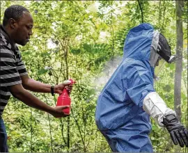  ?? BONNIE JO MOUNT/WASHINGTON POST ?? An epidemiolo­gist sprays disinfecta­nt on CDC scientists in Queen Elizabeth National Park, Uganda, in 2018. The scientists were trying to determine how bats transmit the Marburg virus to humans.