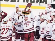  ?? Keith Srakocic / Associated Press ?? UMass’ George Mika (29) holds the NCAA trophy over his head as he skates with the team to celebrate their 5-0 win over St. Cloud State in the Frozen Four championsh­ip game Saturday.