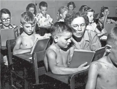  ??  ?? Overcrowde­d and overheated are the prevailing conditions at Frayser Grammar School on 31 Aug 1951. Almost 700 first, second and third graders are finding little elbow room. Miss Marie Watkins, second-grade teacher, offers assistance to Billy Sigler, 7, son of Mr. and Mrs. W.L. Sigler of 1383 Quinby, as Dwight McClain, also 7, of 3093 Signal, waits his turn. And the temperatur­e was hovering at 105 degrees. CHARLES NICHOLAS/THE COMMERCIAL APPEAL FILES