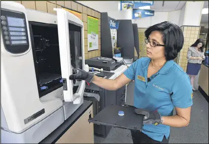  ?? BRANT SANDERLIN PHOTOS / BSANDERLIN@AJC.COM ?? Sejal Zaveri, owner of the UPS Store in Brookhaven, removes a bearing that was printed with a 3-D printer. The store, which started printing in 3-D last year, is one of a few in the chain that offer 3-D printing. Customers include designers, inventors...