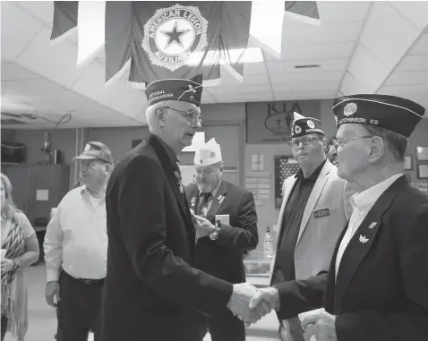  ?? Associated Press ?? National Vice Commander Byron Callies, center, shakes the hand of Marine veteran Gene Haas during a reception at the Hutchinson American Legion Post No. 68 in Hutchinson, Kan. Haas, who has been a member of the American Legion for 64 years, served in...