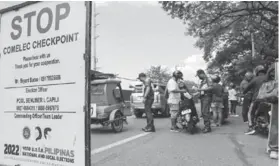  ?? (Jonathan Cellona/ABS-CBN News photo) ?? Members of the Philippine National Police (PNP) inspect documents of motorcycle riders at a PNP-Comelec checkpoint in Marikina City on April 4, 2022.