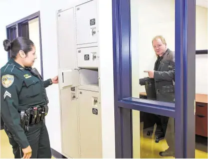  ?? Kim Christense­n / For the Chronicle ?? Deputy Angie Uvalle shows where law enforcemen­t officers will place their gear before entering the room where builder Steve Mataro shows the other side at the new Galveston County Sheriff’s substation in Bacliff.