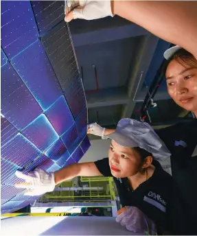  ?? Photo: VCG ?? Workers inspect solar panels at Anhui Daheng Energy Technology in Hefei, Anhui province.