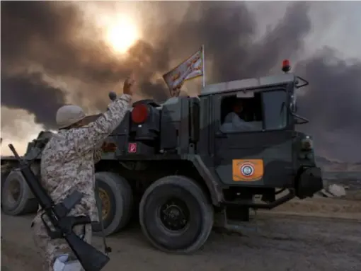  ??  ?? Iraqi troops are seen with the fumes from the sulphur factory in the background (Reuters)
