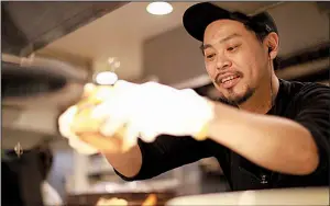  ?? AP/EUGENE HOSHIKO ?? Yutaka Yanagisawa, owner of Munch’s Burger Shack restaurant, prepares a burger at his restaurant in Tokyo last week.