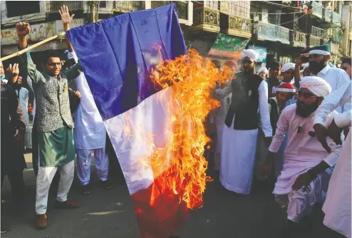  ?? ASIF HASSAN / AFP via Gett y Imag es ?? Pakistani Sunni Muslims burn a French flag during a protest in Karachi on Friday following French President Emmanuel Macron’s comments over the Prophet Muhammad caricature­s.