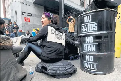  ?? KARL MONDON — STAFF PHOTOGRAPH­ER ?? Elokin Orton-Cheung of Oakiand locks arms with other protesters to block the ICE office in San Francisco on Wednesday.