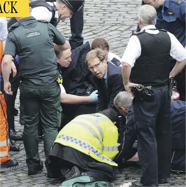  ?? STEFAN ROUSSEAU / PA VIA AP ?? Tobias Ellwood, centre, British member of parliament and a former army officer, works alongside rescue workers as part of a desperate effort to save a police officer who was repeatedly stabbed in a terror attack in London on Wednesday. The officer did...