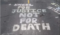  ?? Stephen Maturen / Getty Images ?? “Kneel for Justice not for Death” is written on the road outside the Cup Foods, where George Floyd was killed in police custody in Minneapoli­s.