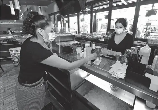  ??  ?? Server Angelica Arciga (left) and bartender Sivanna Guyer fill drink orders at Kona Grill in Boca Park Fashion Village as some businesses that were closed seven weeks ago to fight the spread of the coronaviru­s are allowed to reopen on May 9 in Las Vegas, Nevada. Dozens of US states have recently started to allow certain nonessenti­al businesses to operate, when a nationwide significan­t decline in COVID-19 infections and deaths is yet to come. — AFP