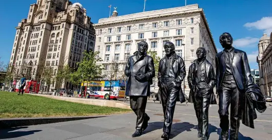  ?? ?? Fab Four: Liverpool’s famous statue of The Beatles strolling along at the Pier Head ... a symbol of a revitalise­d, bustling city