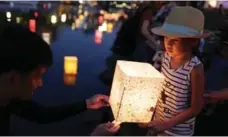  ?? YUYA SHINO/GETTY IMAGES ?? A girl holds a candlelit paper lantern during Saturday’s memorial.