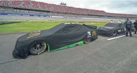  ?? MARVIN GENTRY/USA TODAY SPORTS ?? NASCAR Cup Series cars sit covered on pit road before attempting to start the race Sunday in Talladega, Ala. Officials postponed the playoff race until Monday due to rain.