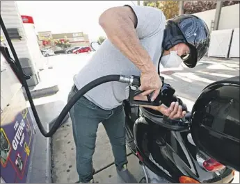  ?? Al Seib Los Angeles Times ?? MARIO ANAYA fills his Vespa at a gas station at the intersecti­on of South Fairfax Avenue and West Olympic and San Vicente boulevards. The state’s average price of a gallon of gas was $4.67 on Sunday.