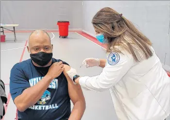  ?? JAMIE BONNEMA ?? Don Huston, an English teacher at Hillcrest High School in Country Club Hills, is vaccinated by Jewel-Osco pharmacy employee Niveen Salah, an alumna of Oak Forest High School, during a District 228 vaccinatio­n event at Bremen High.