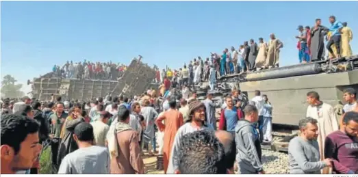  ?? STRINGER / EFE ?? Cientos de personas se congregan ayer en el lugar donde se produjo el trágico choque de trenes en la provincia egipcia de Sohag.