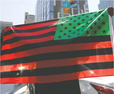  ?? AP PHOTO/NAM Y. HUH ?? A man holds an African-American flag during a demonstrat­ion in Chicago on June 19, 2020, to mark Juneteenth, the holiday celebratin­g the day in 1865 that enslaved black people in Galveston, Texas, learned they had been freed from bondage, more than two years after the Emancipati­on Proclamati­on.