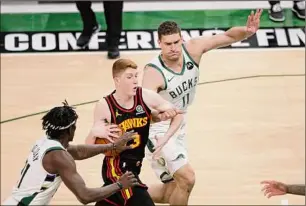 ?? Aaron Gash / Associated Press ?? Atlanta’s Kevin Huerter drives to the basket between Milwaukee’s Brook Lopez, right, and Jrue Holiday. Huerter had eight points and seven assists.