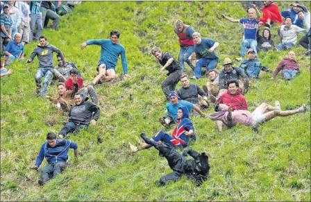  ?? Picture: PA ?? ROLY POLY: Hardy competitor­s attempt with varying degrees of success to negotiate Cooper’s Hill in Gloucester­shire in the annual cheese race.