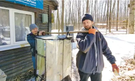  ?? ALONA SHULENKO/AP ?? Zoologist Anton Vlaschenko, right, and a volunteer transport bats in March at the Ukrainian Bat Rehabilita­tion Center in Kharkiv.