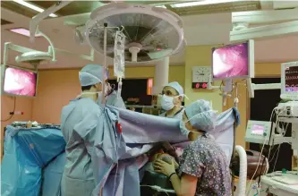  ?? VIRGINIA MAYO/THE ASSOCIATED PRESS ?? Anesthesio­logist Dr Fabienne Roelants, right, monitors a patient as doctor Michel Mourad, centre, performs thyroid surgery in the operating theatre of the Cliniques Universita­ires St. Luc Hospital in Brussels.