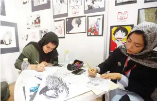  ??  ?? Artists draw manga-style illustrati­ons at a stall during the Libya Comic Convention, in the capital Tripoli on Thursday. (AFP)