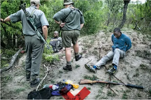  ??  ?? OUTGUNNED: These suspected poachers were caught in Kruger National Park with a .375 hunting rifle fitted with a silencer. Many of the mercenarie­s hired to track poachers are equipped with the latest combat gear.