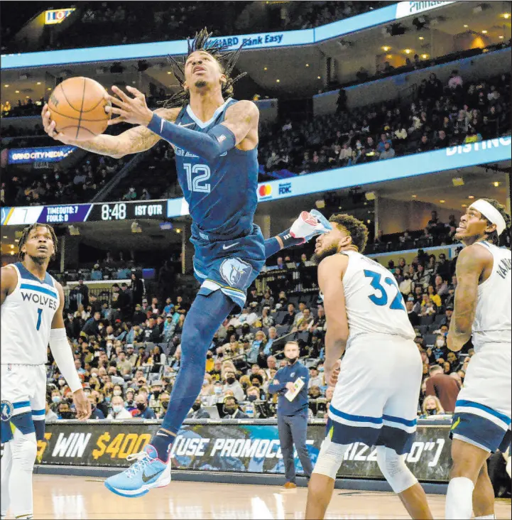  ?? Brandon Dill The Associated Press ?? Grizzlies guard Ja Morant contorts his body for a layup against the Timberolve­s on Jan. 13 in Memphis. Morant has twice been voted Western Conference Player of the
