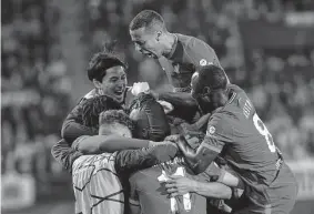  ?? Alberto Saiz / Associated Press ?? The Liverpool players mob Fabinho after he turned the momentum in Tuesday’s game by scoring his team’s first goal in the second half.