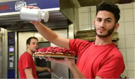  ?? FOTO MIA UYDENS ?? Ayman Al Sammarraie houdt de suiker boven een vruchtenta­art, terwijl bakker Berten Van den Bergh toekijkt.