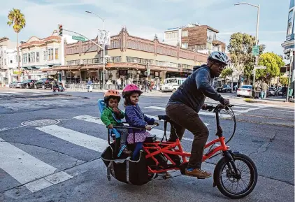  ?? Santiago Mejia/The Chronicle 2020 ?? Ed Parillon rides an electric cargo bike to run errands with son Simon, left, and daughter Louise in the Mission District.
