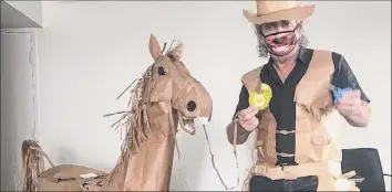  ?? David Marriott / Associated Press ?? David Marriott poses with his paper horse in his hotel room in Brisbane, Australia, on April 1. Marriott was bored while quarantini­ng and started making a cowboy outfit from paper bags.