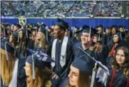  ?? WEST VIRGINIA UNIVERSITY — GEOFF COYLE VIA AP ?? In this photo released by West Virginia University, former West Virginia University and current Oakland Raiders football player Bruce Irvin, center, smiles as he stands arm-in-arm with fellow graduates during the singing of “Country Roads” at the...