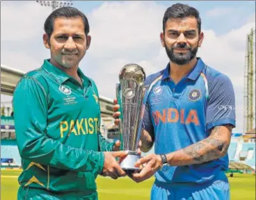  ?? AFP ?? Virat Kohli (R) and Pakistan skipper Sarfraz Ahmed pose with the Champions Trophy.