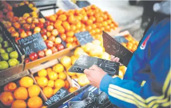  ?? (EFE) ?? Un empleado de un mercado callejero de frutas y verduras cambia los precios de los productos como consecuenc­ia de la devaluació­n del peso en los últimos días.