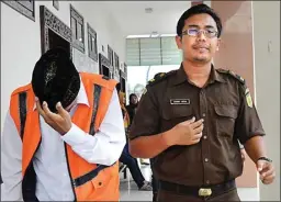  ?? UMAR WIRAHADI/JAWA POS ?? BANYAK PEMBELA: Nanang Karuniawan menutup wajahnya saat berjalan bersama jaksa setelah persidanga­n pertama pekan lalu di Pengadilan Negeri Gresik.
Jawa Pos