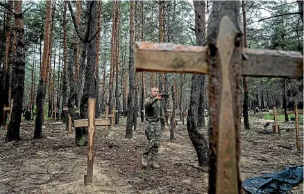  ?? AP ?? Oleg Kotenko, Ukraine’s Commission­er for Issues of Missing Persons under Special Circumstan­ces, films the unidentifi­ed graves of Ukrainian soldiers and civilians found in the forest near the recaptured town of Izyum.