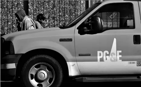  ?? AP Photo/Jeff Chiu ?? In this photo taken Feb. 18, shows people walk behind a Pacific Gas and Electric truck parked in San Francisco.