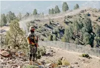  ??  ?? A soldier stands guard along the border fence at the Angoor Adda outpost on the border with Afghanista­n in Waziristan. —