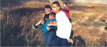  ?? Reuters ?? ↑
Men carry a boy as Palestinia­ns take part in a protest east of Gaza City on Thursday.