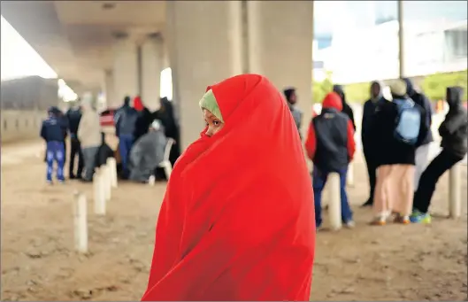  ?? Picture HENK KRUGER ?? ‘GIVE ME SHELTER’: Raho Hassen waits with others under the Nelson Mandela Boulevard Bridge for her name to be called by Home Affairs officials.