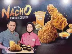  ??  ?? KAKITANGAN KFC menunjukka­n hidangan ayam goreng terbaru KFC Nacho Cheezy Crunch.