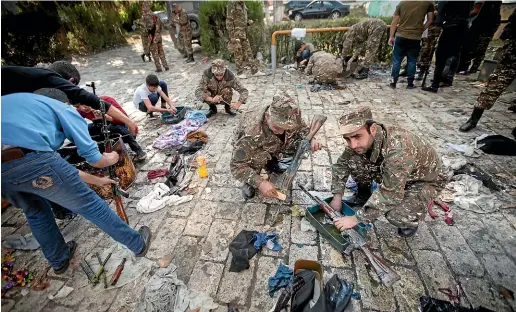  ?? AP ?? Young volunteers help soldiers to clean Kalashniko­vs guns coated with preservati­ve grease near Hadrut in the self-proclaimed Republic of Nagorno-karabakh, Azerbaijan.