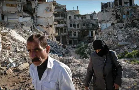  ?? Fotos Yan Boechat/Folhapress ?? Casal passa por meio de escombros de bairro da cidade de Aleppo; abaixo, moradores compram produtos em mercado