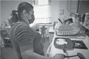  ?? ROBERT BUMSTED/ASSOCIATED PRESS ?? Candida Uraga prepares a meal March 21 in the kitchen of her apartment in New York. She has struggled to pay rent after being laid off from her job as a teaching assistant during the pandemic and was denied help under a federally funded rental assistance program.