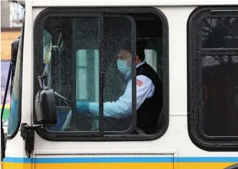  ?? HERALD STAFF FILE; LEFT, MATT STONE / HERALD STAFF FILE ?? SHOWING THEIR DRIVE: An MBTA bus driver wears a mask while driving along Broadway on April 13 in Chelsea, and at left, the Greenbush commuter rail stops at the East Weymouth MBTA station on Dec. 11, with carmen working straight through the pandemic despite possible exposure.