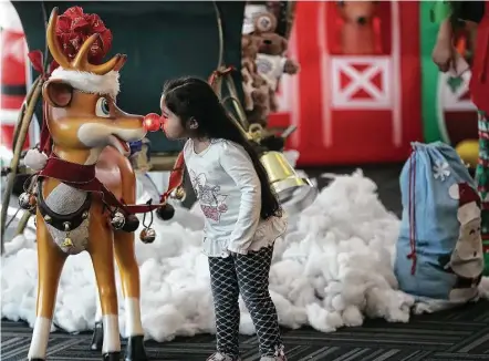  ?? Elizabeth Conley / Houston Chronicle ?? Rubi Noyola, 3, goes nose to nose with Rudolph in the North Pole at Bush Interconti­nental Airport during United’s Fantasy Flight event.