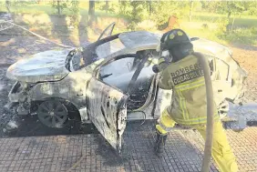  ?? ?? Un bombero de Ciudad del Este apaga el fuego dentro del auto de los asaltantes.