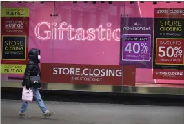  ?? PHOTOS BY KIRSTY WIGGLESWOR­TH — THE ASSOCIATED PRESS ?? A woman walks past the window of a closed shop on Oxford Street in London on Saturday.